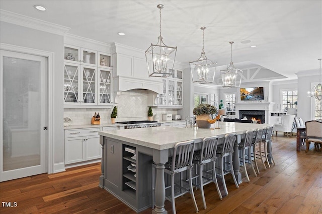 kitchen with a spacious island, a fireplace, white cabinets, ornamental molding, and decorative backsplash