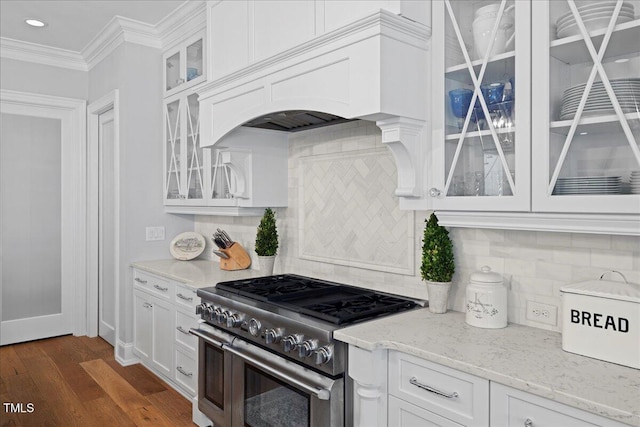 kitchen with light stone counters, dark wood finished floors, high end stainless steel range, ornamental molding, and white cabinets