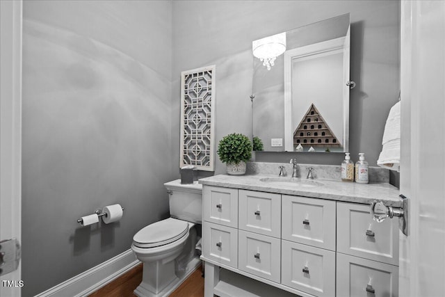 bathroom featuring wood finished floors, vanity, toilet, and baseboards