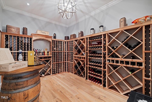 wine cellar with crown molding, an inviting chandelier, and hardwood / wood-style flooring