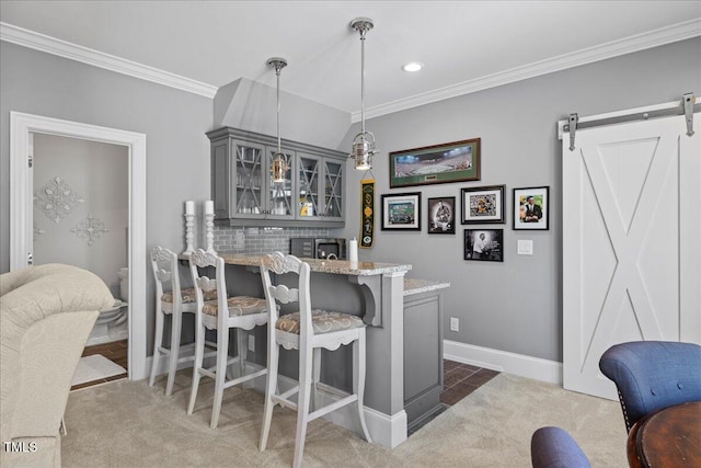 bar with carpet, a barn door, ornamental molding, and pendant lighting