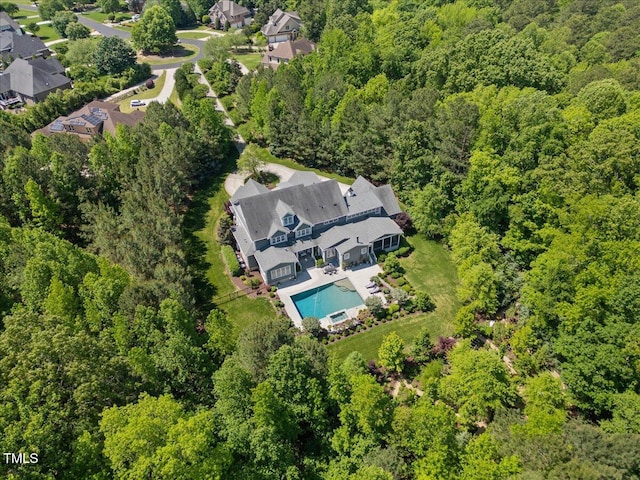 drone / aerial view featuring a wooded view and a residential view