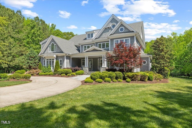 view of front facade featuring covered porch, curved driveway, and a front lawn