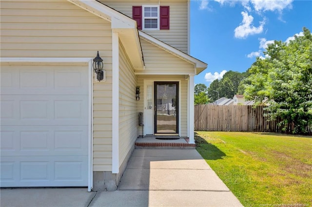 property entrance with a yard, an attached garage, and fence