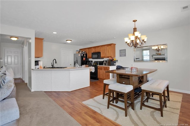 dining room featuring light wood finished floors, baseboards, visible vents, and a notable chandelier