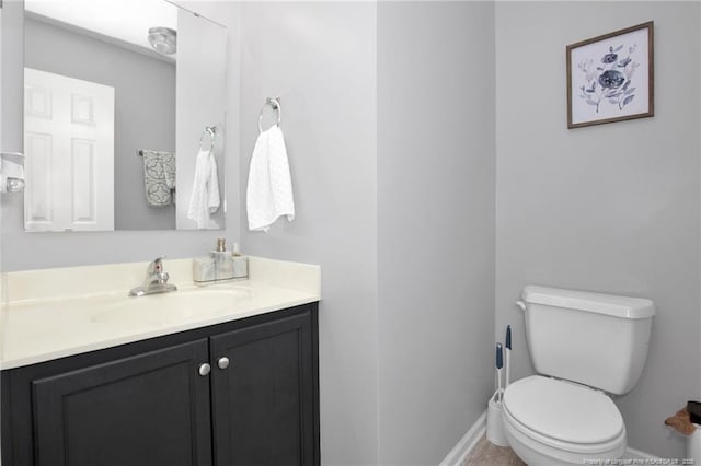 bathroom featuring toilet, baseboards, and vanity