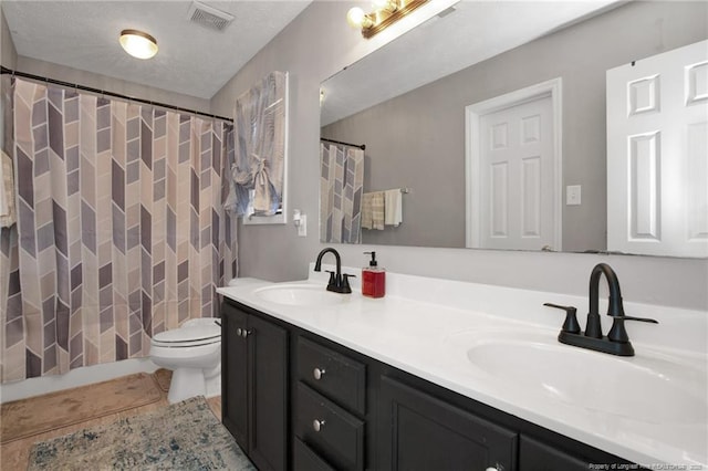 bathroom with visible vents, a sink, toilet, and double vanity