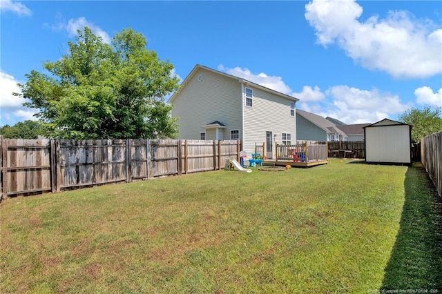 view of yard with a storage shed, a fenced backyard, a deck, and an outbuilding