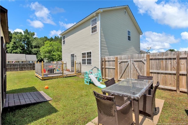 back of house with a fenced backyard, outdoor dining area, a lawn, and a wooden deck