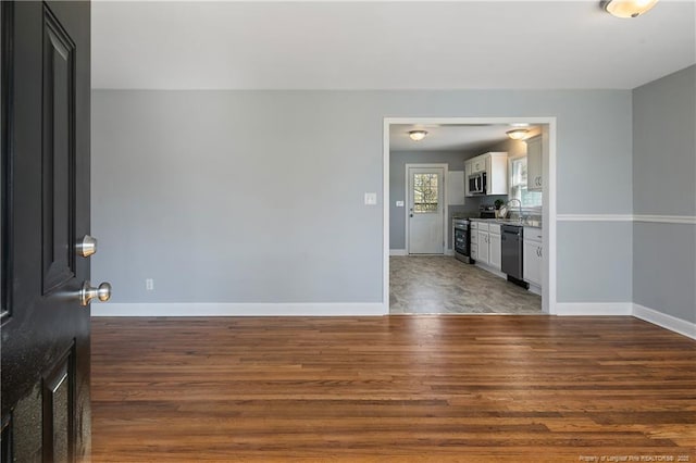 spare room featuring dark wood-style floors and baseboards