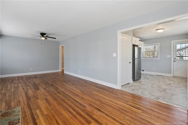 unfurnished living room with ceiling fan, baseboards, and wood finished floors