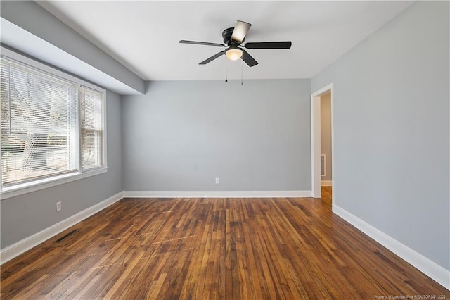 unfurnished room featuring dark wood-style flooring, visible vents, ceiling fan, and baseboards