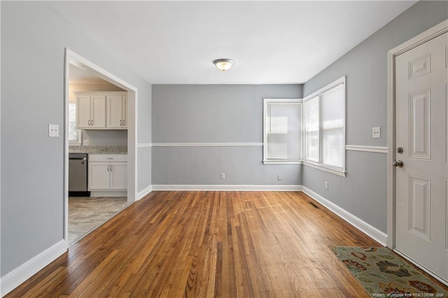 unfurnished dining area with light wood-style flooring and baseboards