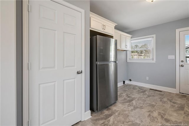 kitchen featuring baseboards and freestanding refrigerator