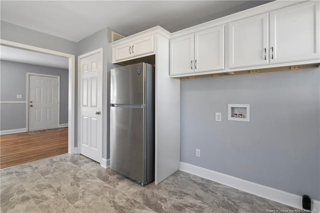 kitchen with freestanding refrigerator, white cabinets, and baseboards