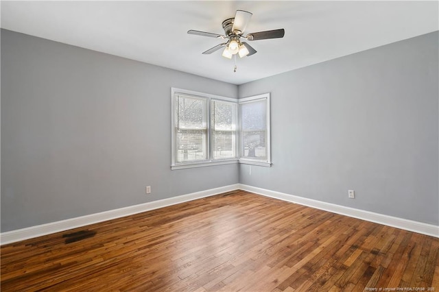 empty room featuring ceiling fan, baseboards, and wood finished floors