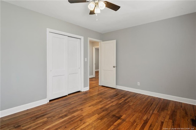 unfurnished bedroom with a ceiling fan, a closet, baseboards, and dark wood-style flooring