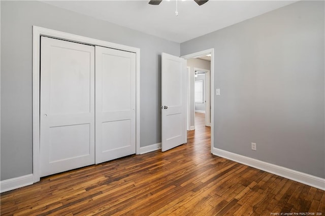 unfurnished bedroom with ceiling fan, dark wood-type flooring, a closet, and baseboards