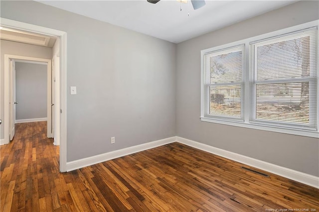 unfurnished room with dark wood-type flooring, a ceiling fan, visible vents, and baseboards