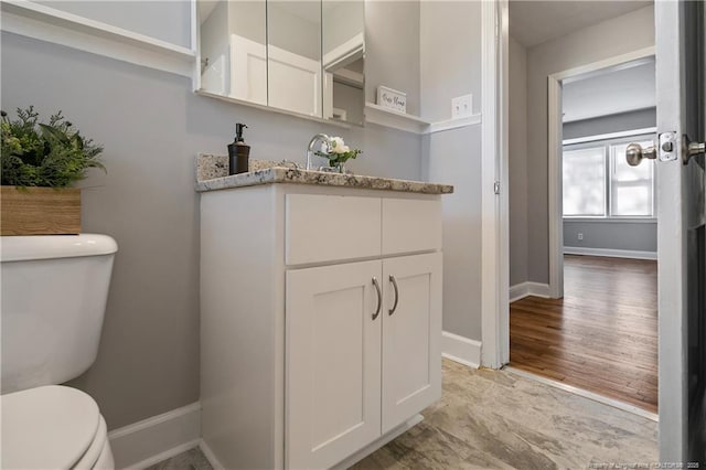 bathroom featuring baseboards, vanity, toilet, and wood finished floors