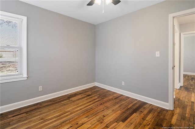 spare room with ceiling fan, baseboards, and dark wood-type flooring