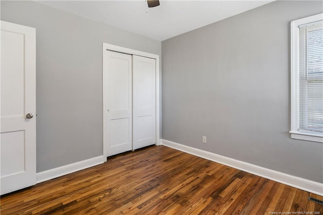 unfurnished bedroom featuring visible vents, baseboards, dark wood-style floors, ceiling fan, and a closet