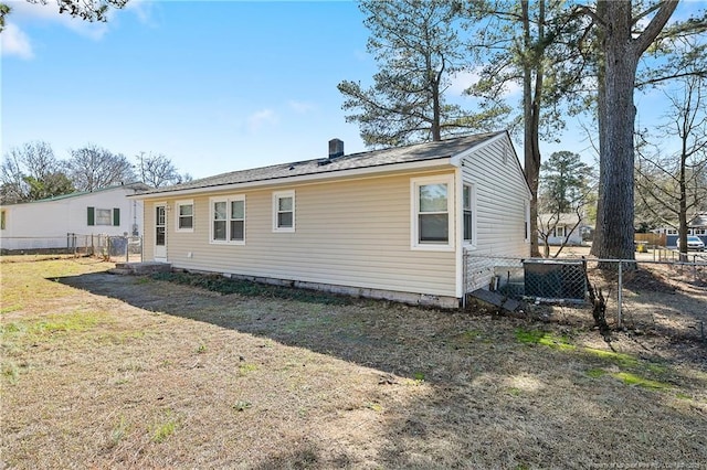 back of property featuring a yard, cooling unit, and fence