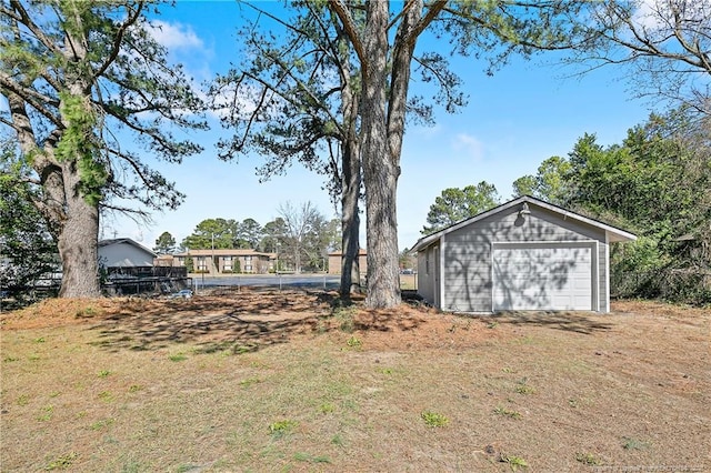 view of yard with an outbuilding, a detached garage, and driveway