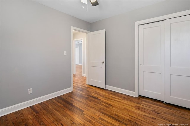 unfurnished bedroom featuring ceiling fan, a closet, baseboards, and dark wood-style flooring