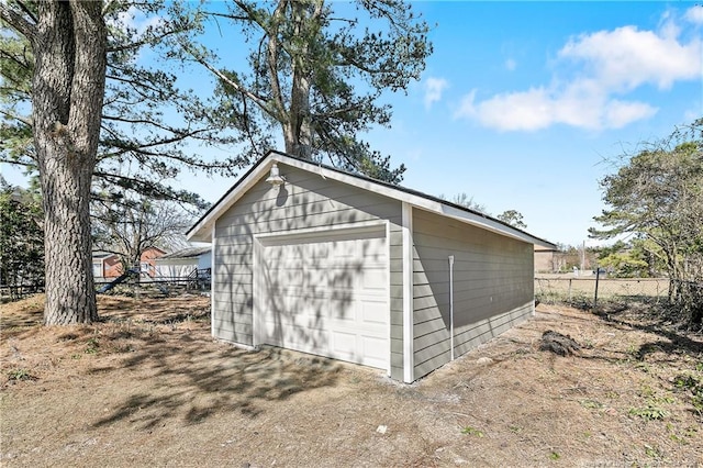 detached garage featuring fence and dirt driveway