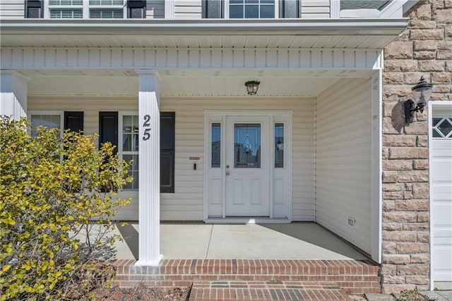 doorway to property featuring stone siding, brick siding, and covered porch