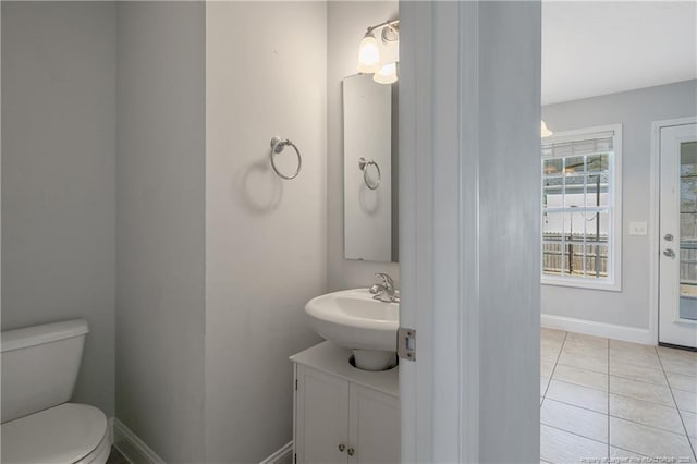 half bathroom with vanity, tile patterned floors, toilet, and baseboards