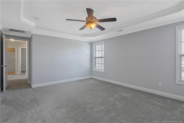 empty room with carpet, visible vents, and a raised ceiling