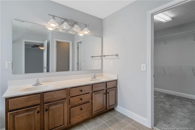 full bathroom featuring double vanity, tile patterned flooring, a sink, and a walk in closet