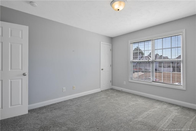 unfurnished room featuring carpet flooring and baseboards