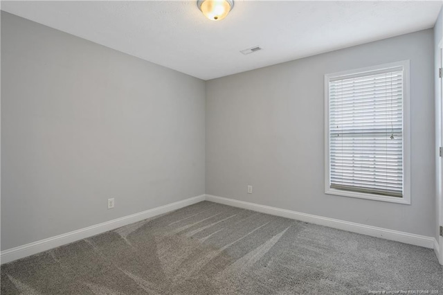 carpeted spare room featuring visible vents and baseboards