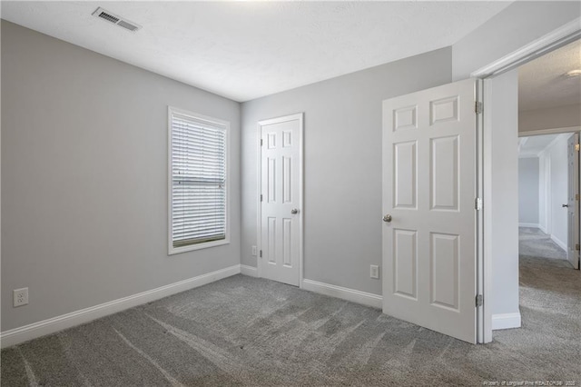 carpeted spare room featuring baseboards and visible vents