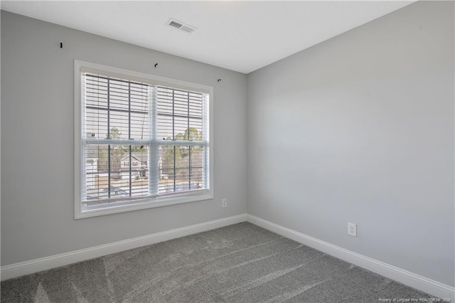 unfurnished room with carpet, visible vents, and baseboards