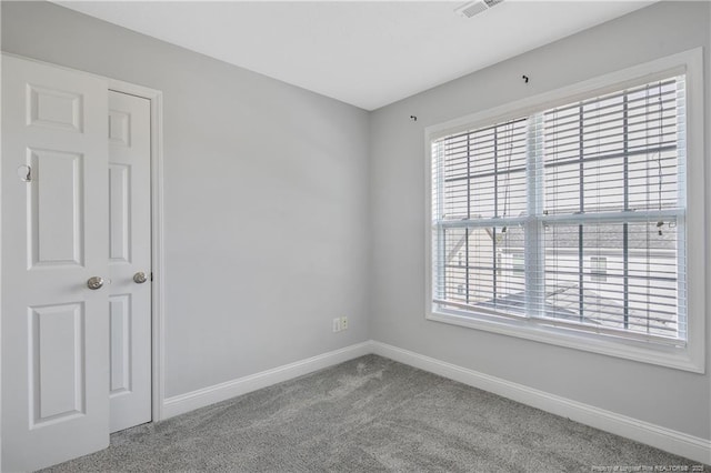 carpeted spare room featuring visible vents and baseboards