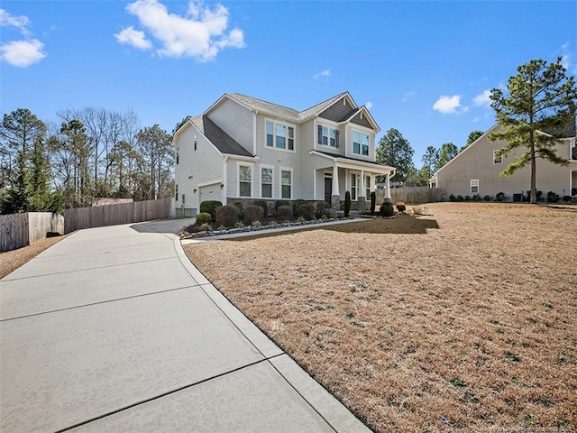 view of front facade featuring covered porch, driveway, and fence