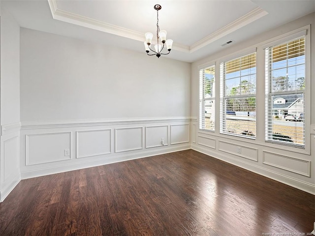 spare room with a tray ceiling, a chandelier, dark wood-style flooring, and ornamental molding