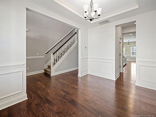 unfurnished room featuring a tray ceiling, dark wood-style flooring, visible vents, stairway, and an inviting chandelier