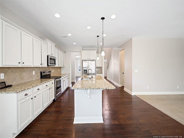 kitchen with a kitchen island with sink, stainless steel appliances, a sink, white cabinets, and decorative light fixtures