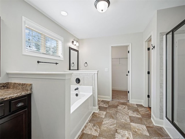 full bathroom featuring a spacious closet, a stall shower, vanity, and a bath