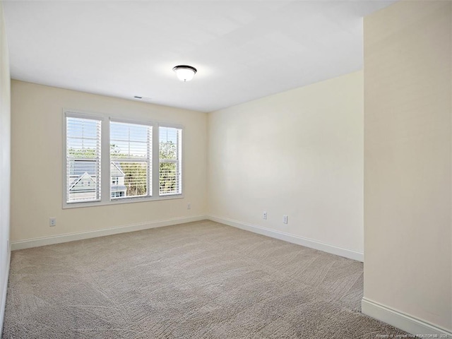 unfurnished room featuring light colored carpet and baseboards