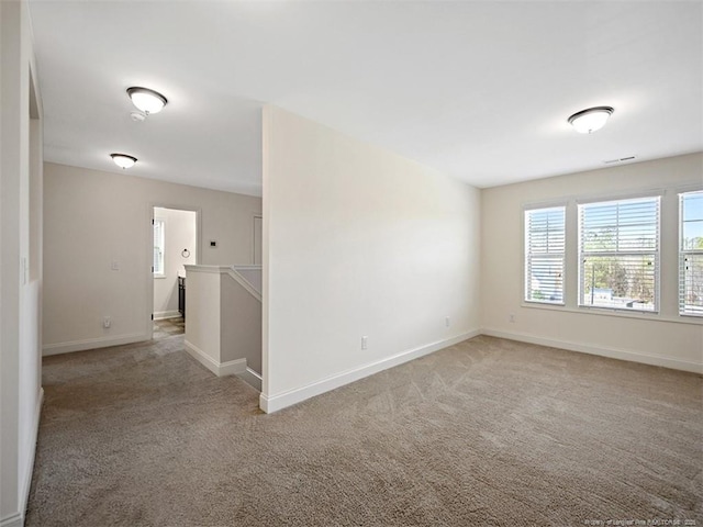 unfurnished room with light colored carpet, visible vents, and baseboards