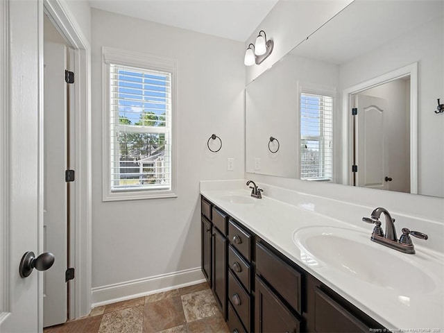 bathroom with a healthy amount of sunlight, baseboards, and a sink