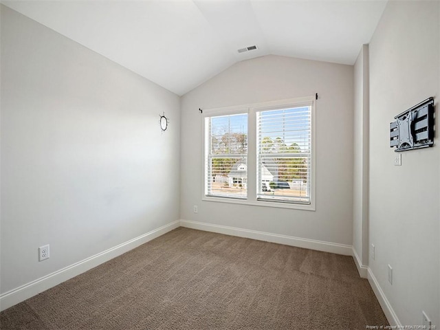 carpeted spare room featuring baseboards, visible vents, and vaulted ceiling