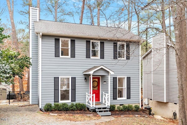 colonial-style house featuring crawl space, a chimney, fence, and roof with shingles