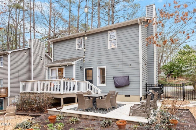 rear view of property with fence, crawl space, a wooden deck, a chimney, and a patio area